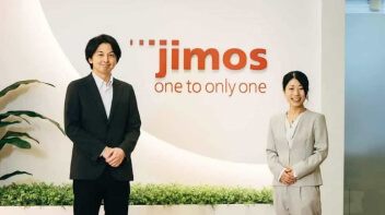 株式会社JIMOSのみなさんとロゴが写っている写真